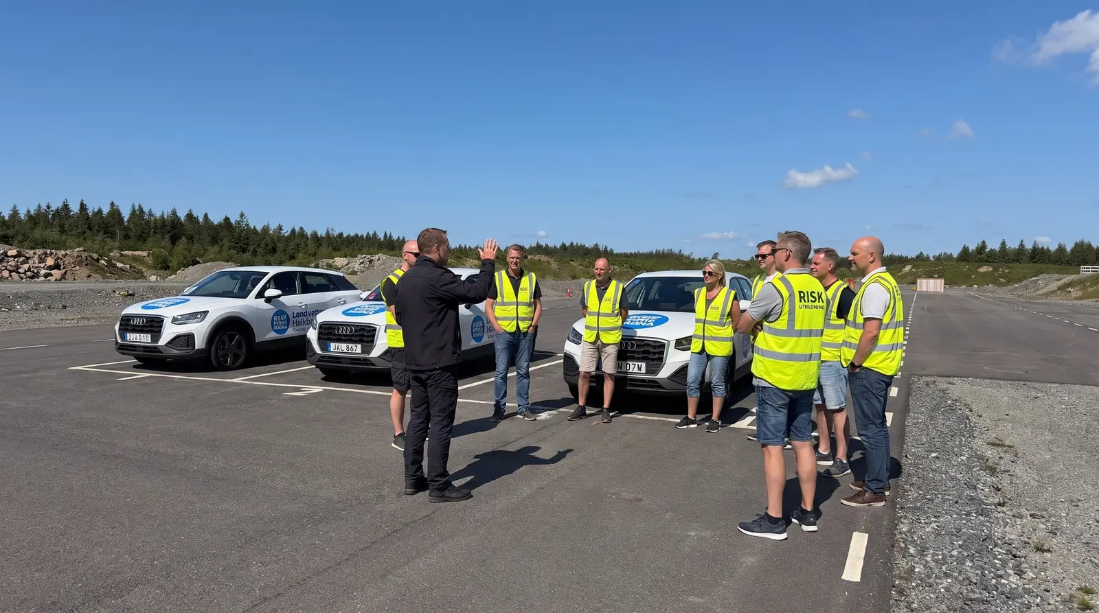 Illustration: colleagues in yellow vests listening to an instructor next to the training cars on the track