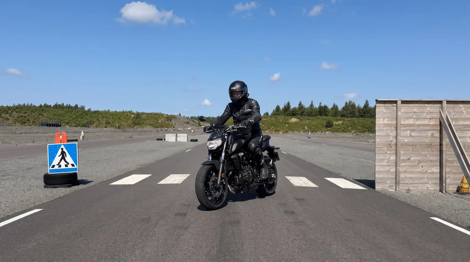 Illustration: motorcyklist saktar in före övergångsstället på banan