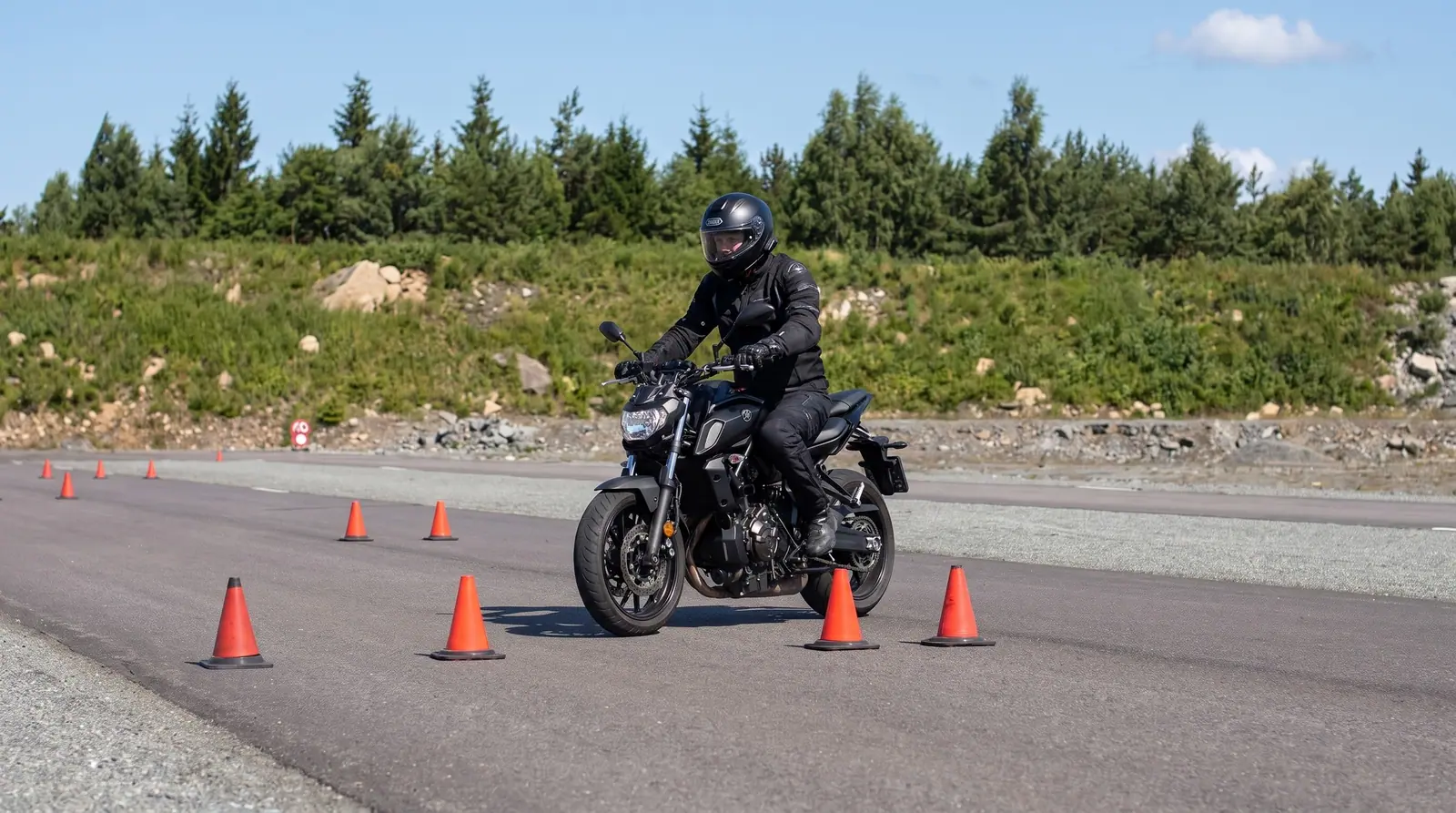 Illustration: motorcyklist kör slalom mellan koner på halkbanan